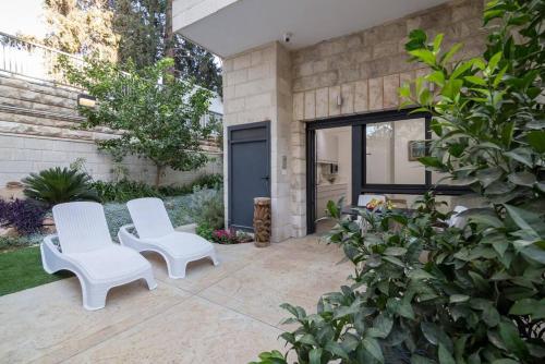 2 sillas blancas sentadas en un patio en New luxurious apt, the BEST location in Jerusalem, en Jerusalén