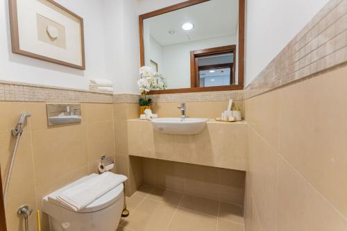 a bathroom with a toilet and a sink and a mirror at WORLD CLASS 3BR with full BURJ KHALIFA and FOUNTAIN VIEW in Dubai