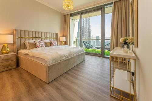 a bedroom with a large bed and a large window at WORLD CLASS 3BR with full BURJ KHALIFA and FOUNTAIN VIEW in Dubai