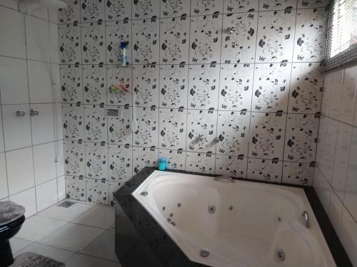 a bath tub in a bathroom with a tile wall at Casa de temporada in São João Batista do Glória