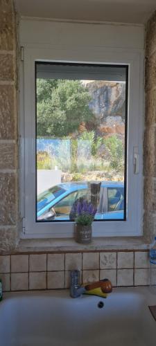 una ventana en una cocina con fregadero frente a un fregadero en Πέτρα, Ελιά και Λεβάντα, en Tolo