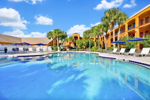 ein großer Pool in einem Hotel mit Stühlen und Sonnenschirmen in der Unterkunft Mi Casa Hotel in Orlando