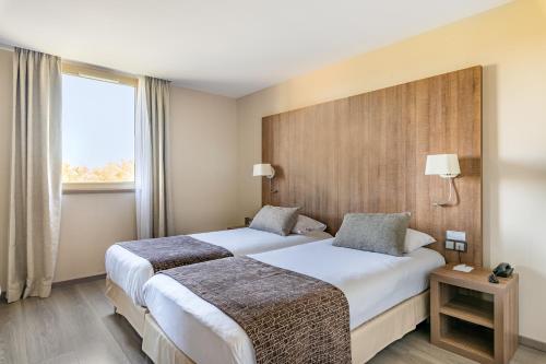 Habitación de hotel con 2 camas y ventana en Best Western Hôtel des Barolles - Lyon Sud, en Brignais