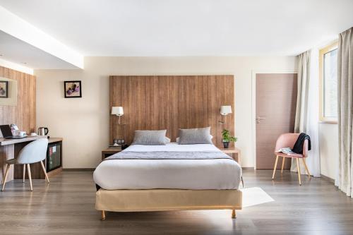 a bedroom with a large bed and a desk at Best Western Hôtel des Barolles - Lyon Sud in Brignais