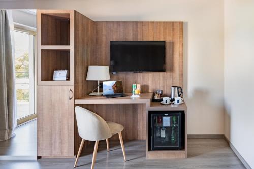 a room with a desk with a chair and a television at Best Western Hôtel des Barolles - Lyon Sud in Brignais