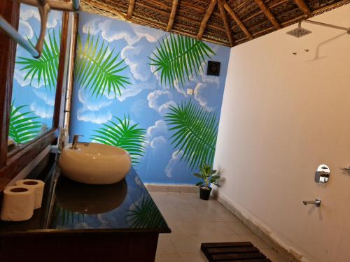 uma casa de banho com um lavatório e um mural com folhas de palmeira. em Agonda Wellness em Agonda