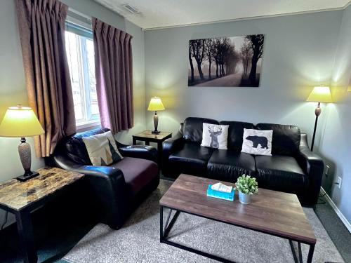 a living room with black leather furniture and a table at Canadian Rockies Chalets by Trilink - 2 & 3 Bedroom Condos - Self Check-In - Walking Distance to Downtown - Free Parking - Pet-Friendly - No AC in Canmore