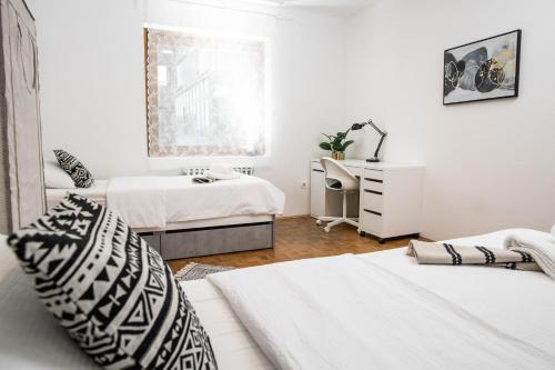 a white bedroom with two beds and a window at Apartman Tihana in Vinkovci