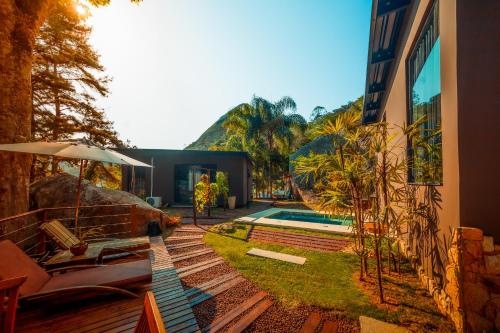 uma casa com piscina e algumas cadeiras e um guarda-sol em Cabana Secreta em Petrópolis