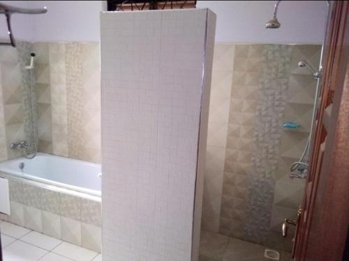 y baño con bañera, ducha y bañera. en PALATINE APARTMENTS MAKINDYE KIZUNGU, KAMPALA, en Kampala