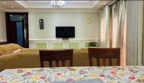 a dining room with a table and chairs and a television at PALATINE APARTMENTS MAKINDYE KIZUNGU, KAMPALA in Kampala