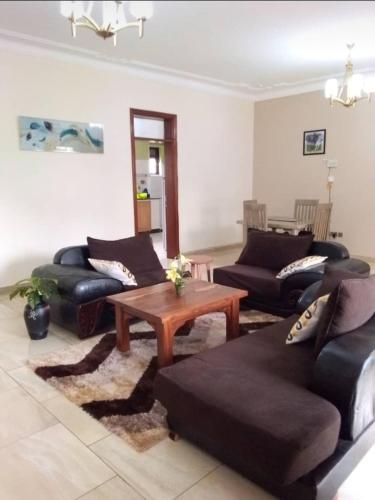 a living room with couches and a coffee table at PALATINE APARTMENTS MAKINDYE KIZUNGU, KAMPALA in Kampala