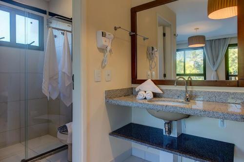 a bathroom with a sink and a mirror and a shower at Condomínio no melhor da Praia de Cumbuco por Carpediem in Cumbuco