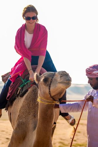 a woman riding on the back of a camel at Luxury Desert Camp Oman in Al Wāşil