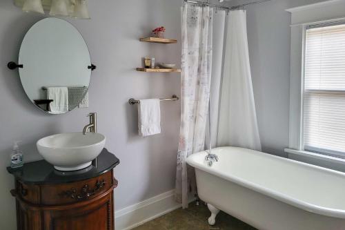 a bathroom with a tub and a sink and a mirror at Charming Home Less Than One block to Lake Superior! in Ontonagon