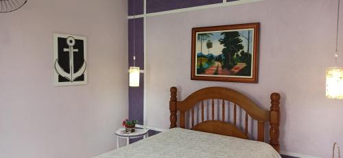 sypialnia z łóżkiem i zdjęciem na ścianie w obiekcie Espaço Aconchego com ar-condicionado e amplo jardim w mieście Caraguatatuba