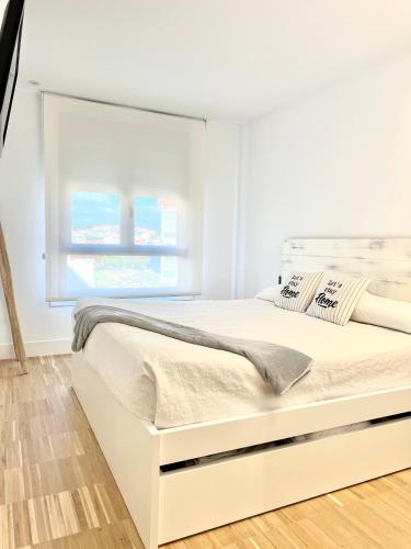 uma cama branca num quarto com uma janela em Apartamento nuevo en playa Sanxenxo, con garaje em Sanxenxo