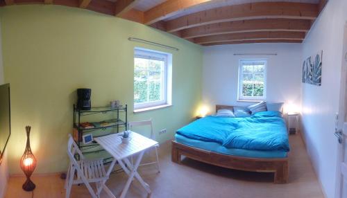 een slaapkamer met een bed, een tafel en 2 ramen bij Privatzimmer im Schwedenhaus Unsere Kleine Farm in Monschau