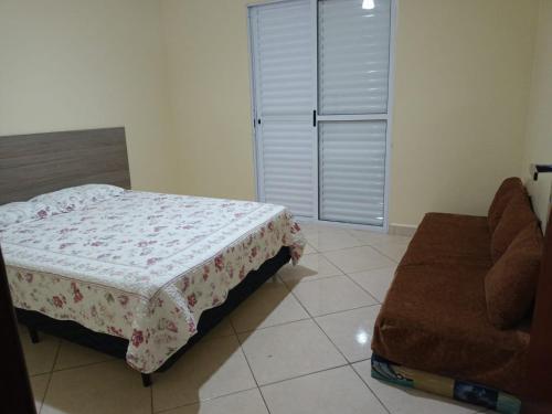 a bedroom with a bed and a couch in it at Lindo Sobrado in Mongaguá