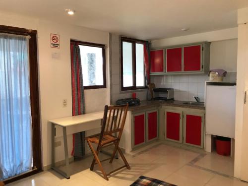 a kitchen with red cabinets and a desk and a chair at CASA MOSAICO in Puerto López