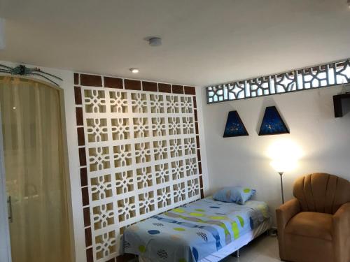 a bedroom with a bed and a chair and a window at CASA MOSAICO in Puerto López