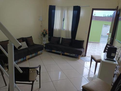 a living room with two black couches and a window at Lindo Sobrado in Mongaguá
