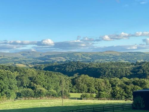 a view of a green field with trees and hills at Ravens Rest in Llanwrda