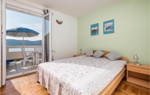 ein Schlafzimmer mit einem Bett und einem Balkon mit einem Sonnenschirm in der Unterkunft Lovely Apartment In Stara Novalja With House Sea View in Stara Novalja