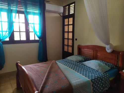 a bedroom with a bed and two windows at Chambres d'hôte Sud Basse-Terre in Gourbeyre