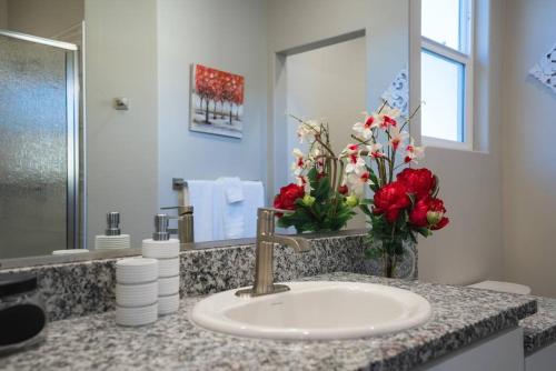 a bathroom with a sink and a vase of red flowers at Majestic Zion Cottage with hot tub in Hildale in Hildale