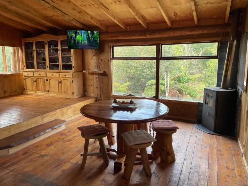 una habitación con mesa y taburetes en una cabaña en Cabañas Lickanantay, en Puerto Varas