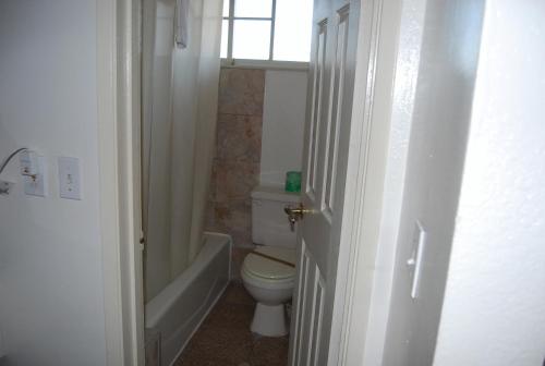 a bathroom with a toilet and a tub and a window at Stanford Motor Inn in Palo Alto