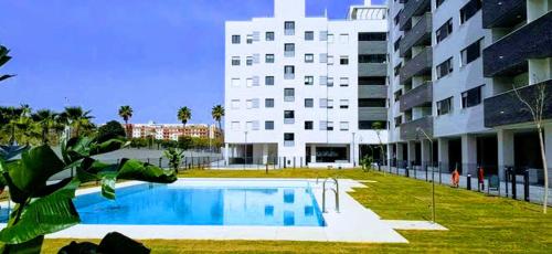 a swimming pool in front of a large building at Ático con Piscina y Vistas al Mar Parque Litoral in Málaga