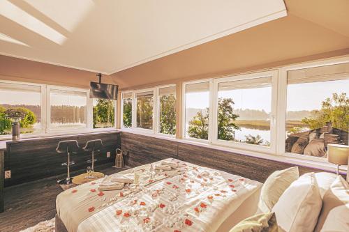 a bedroom with a large bed and windows at Mártoni Resort & Restaurant in Szigetszentmárton