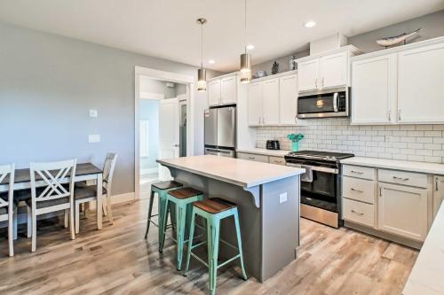 a kitchen with white cabinets and a table with stools at Ocean Shores Getaway with Fireplace and Hot Tub! in Ocean Shores