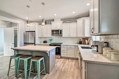 a kitchen with white cabinets and a island with stools at Ocean Shores Getaway with Fireplace and Hot Tub! in Ocean Shores