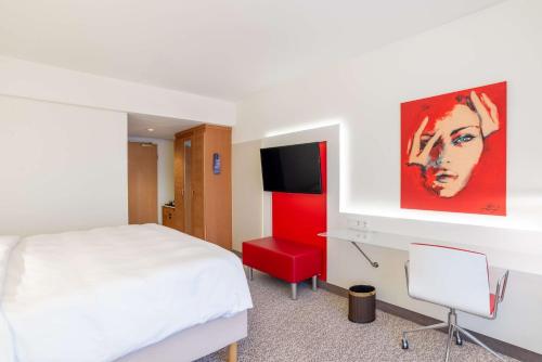 a hotel room with a bed and a tv at Radisson Blu Hotel Karlsruhe in Ettlingen
