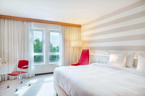 a hotel room with a bed and a red chair at Radisson Blu Hotel Karlsruhe in Ettlingen