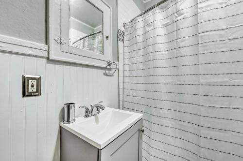 La salle de bains blanche est pourvue d'un lavabo et d'un miroir. dans l'établissement Charming Charlotte Abode with Deck and Fire Pit!, à Charlotte