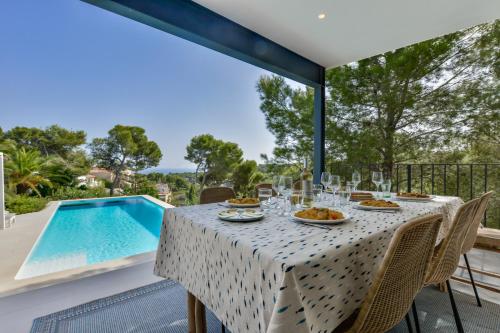 a table with food and wine on a balcony with a swimming pool at Buenavista by Almarina Villas in Benissa