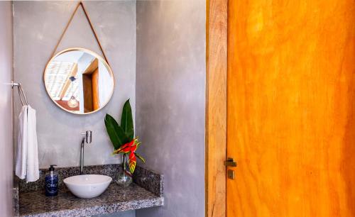 een badkamer met een wastafel en een spiegel bij Suítes Las Flores Maresias in Maresias