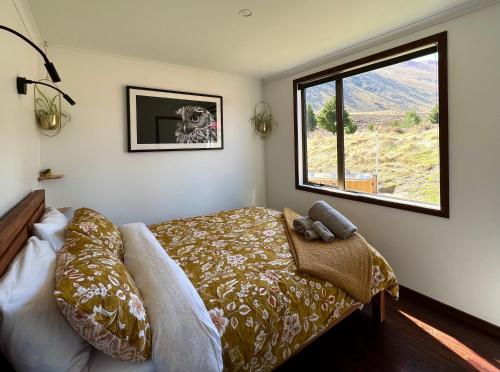 a bedroom with a bed and a large window at MenardsNZ Ecosanctuary Accommodation in Twizel