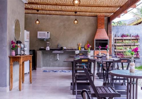 a restaurant with tables and chairs and a kitchen at Suítes Las Flores Maresias in Maresias