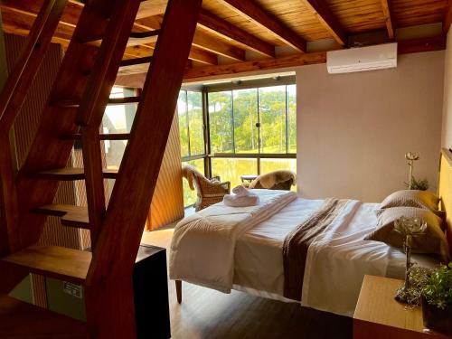 a bedroom with a large bed and a staircase at WoodStone Hotel Fazenda in Gramado