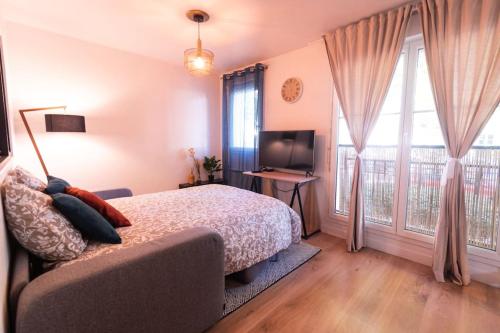 a bedroom with a bed and a television and windows at Le Cocon-T2-40m2-Centre ville 10min Disney in Bussy-Saint-Georges