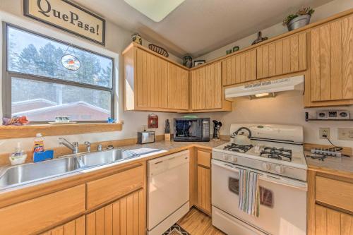 a kitchen with wooden cabinets and a white stove top oven at Charming Coppertop Cloudcroft Cabin 3 Mi to Ski in Cloudcroft