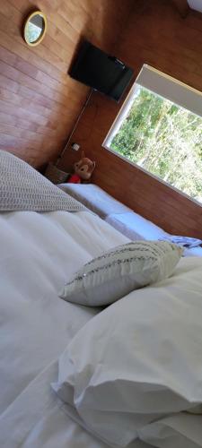 a bedroom with two white beds and a window at Acogedora cabaña en el bosque, acceso vehiculos 4x4 in Cochamó