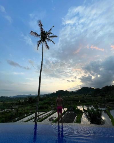 a man standing next to a palm tree at Villa di Bias in Tirtagangga