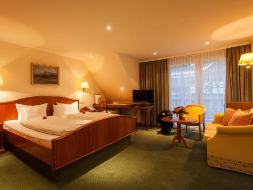 um quarto de hotel com uma cama grande e uma cadeira em Romantik Hotel zur Sonne em Badenweiler