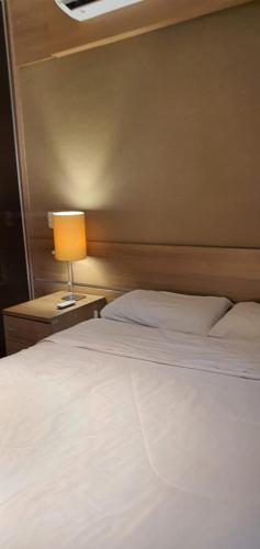 a bedroom with a white bed and a lamp at Grand Loft - Amazing Duplex 314 in Sao Paulo